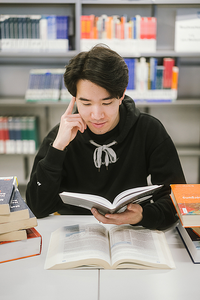 Student liest in der Bibliothek ein Buch